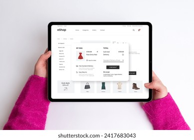 E-commerce cart page on a tablet with price, delivery options, and checkout button. Woman buys a red dress, creating a seamless and stylish online shopping experience - Powered by Shutterstock