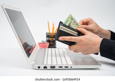 E-commerce concept. A man's hand pulls money out of his wallet in front of a laptop monitor.