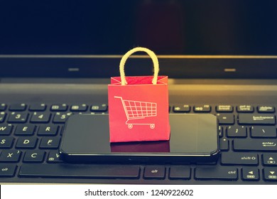 Konzept des elektronischen Geschäftsverkehrs. : Red Paper Einkaufstaschen mit Smartphone auf Notebook-Tastatur. Internationaler Fracht- oder Versanddienst für Online-Einkäufe