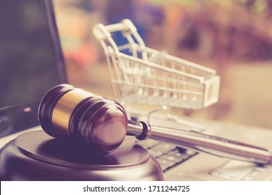 E-commerce law, rules and regulations concept : Wooden judge gavel and shopping cart on a laptop, depicts good practice vendor must do for consumer e.g provide clear data, order cancellation, refund