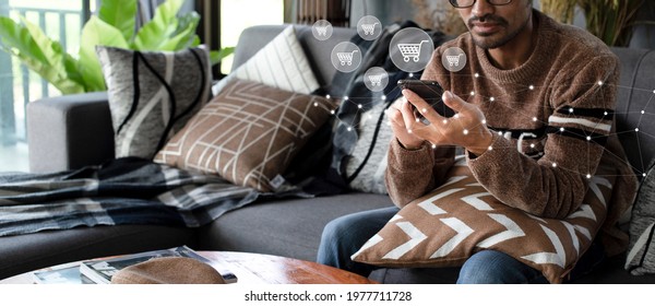 E-commerce And Online Shopping Concept With People Using Smartphone With Shopping Cart Icon And Network While Sitting On Sofa In Living Room At Home