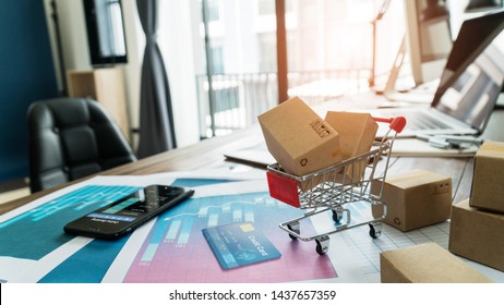 E-commerce. Paper boxes in shopping cart and credit card with smartphone on sales data economic growth graph, online shopping and payments, banking, buying and selling services online on network.