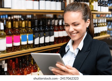 E-commerce for the sale of wine and alcoholic beverages. Young business woman working on a digital laptop in a liquor store.