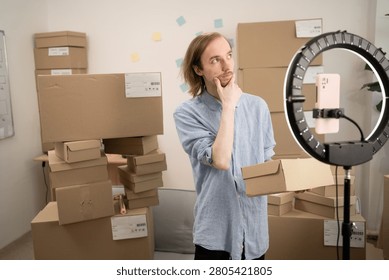 ecommerce, sme and post logistic concept. Focused vlogger or blogger SME small business owner hipster man using ring light and mobile phone to sell products thinking strategy idea online live stream