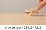 Economic, business outlook concept. Financial, business view or economic growth forecast for 2025. OUTLOOK 2025 text and binoculars icon on wooden cube blocks, copy space and minimal background.