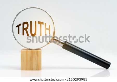 Economic concept. On a white surface there is a cube and a magnifying glass inside which is the inscription - TRUTH