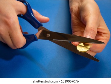 Economic And Financial Crisis Concept. Scissors Cut Euro Coin On Blue Background. Saving Money To Pay Taxes And Debts. Funds From The European Union. Salary Cuts.