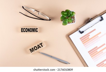 ECONOMIC MOAT Text On A Wooden Block With Chart And Glasses, Business Concept