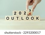 Economic outlook concept. Financial, business review or economic growth forecast for 2024. Turning OUTLOOK 2023 to 2024  text on wooden cube blocks.