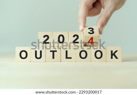 Economic outlook concept. Financial, business review or economic growth forecast for 2024. Turning OUTLOOK 2023 to 2024  text on wooden cube blocks.