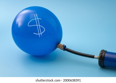 Economic recession, assets bubble and currency inflation concept with manual handpump inflating a balloon with a dollar sign on it isolated on blue background