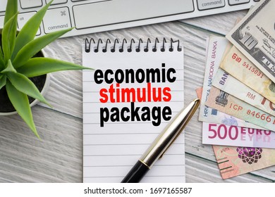 ECONOMIC STIMULUS PACKAGE Text With Notepad, Keyboard, Decorative Vase, Fountain Pen, Calculator And Banknotes Currency On Wooden Background. Business And Copy Space Concept