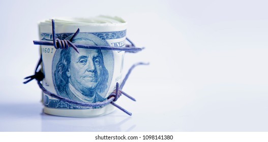 Economic Warfare, Sanctions And Embargo Busting Concept. US Dollar Money Wrapped In Barbed Wire.