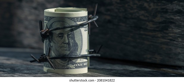 Economic Warfare, Sanctions And Embargo Busting Concept. Close Up US Dollar Money Wrapped In Barbed Wire. Horizontal Image.