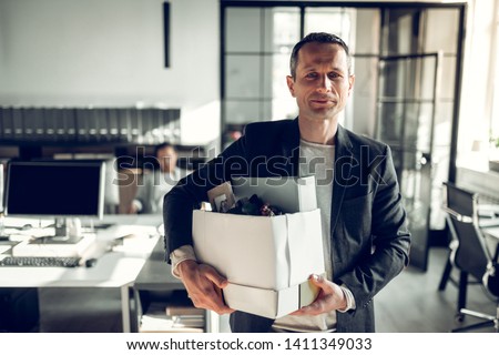 Economist leaving office. Handsome economist leaving the office taking his box with different things