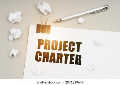 Economy and business concept. On a gray surface, a pen, crumpled paper and a sheet with the inscription - Project Charter