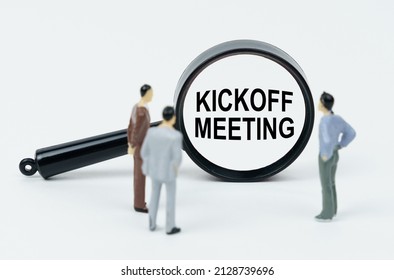 Economy And Business Concept. On A White Background There Are Figures Of Businessmen And A Magnifying Glass, Inside Of Which There Is An Inscription - Kickoff Meeting