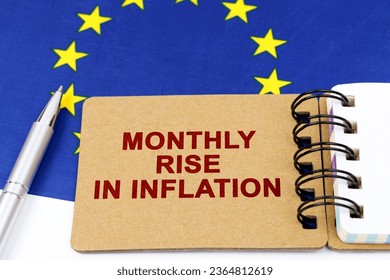 Economy and finance concept. On the flag of the European Union lies a pen and a notepad with the inscription - monthly rise in inflation. - Shutterstock ID 2364812619