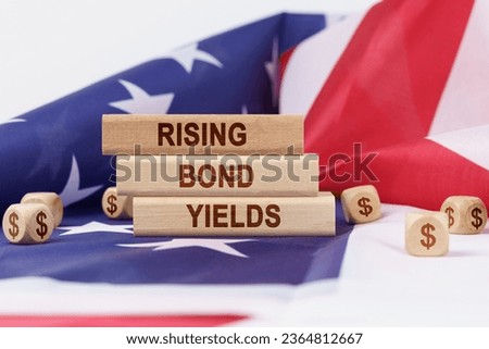 Economy and finance concept. On the flag of the United States lie cubes with the dollar symbol and wooden dies with the inscription - rising bond yields.