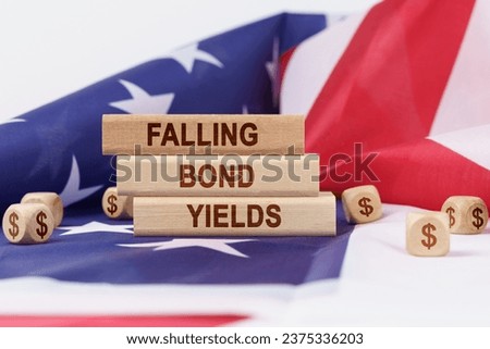Economy and finance concept. On the flag of the United States lie cubes with the dollar symbol and wooden dies with the inscription - falling bond yields.