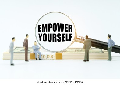 Economy and finance concept. On a white background, coins, a pack of dollars, figures of businessmen who look at a magnifying glass with the inscription - Empower Yourself