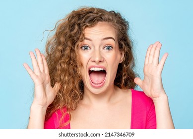 Ecstatic Caucasian woman screaming with open hands in isolated light blue color studio background