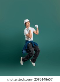 Ecstatic construction worker jumping for joy in work attire against a solid background, celebrating a job well done!