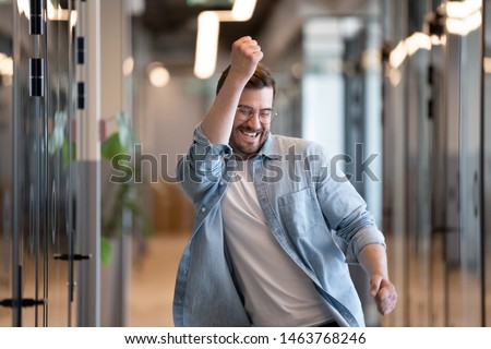 Ecstatic excited male winner dancing in office hallway laughing celebrating work achievement professional win, happy overjoyed business man enjoy victory dance euphoric about success reward promotion