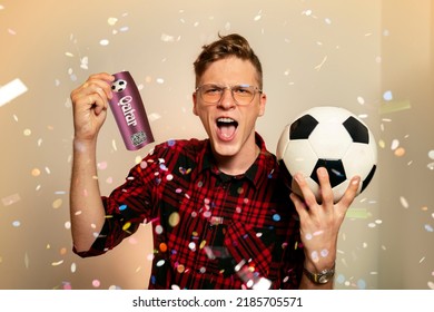 Ecstatic fan, young man holding ticket for soccer match and soccer ball. Confetti in the back. Man winning ticket as prize 