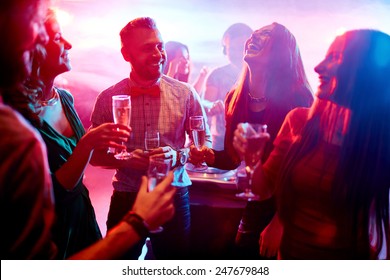 Ecstatic Friends With Champagne Talking At Party In Night Club