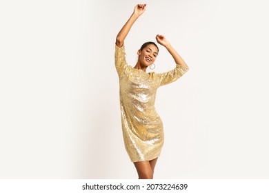 Ecstatic mix race  woman in golden sequins  party dress   dancing and having fun  on white background.  Celebrating new year party.
