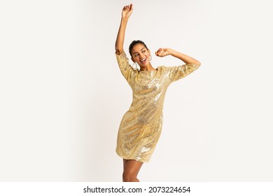 Ecstatic mix race  woman in golden sequins  party dress   dancing and having fun  on white background.  Celebrating new year party.