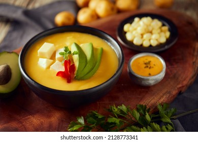 Ecuadorian locro de papa a traditional potato and cheese soup served with avocado and hominy. It’s on a wooden background - Shutterstock ID 2128773341