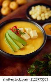 Ecuadorian locro de papa a traditional potato and cheese soup served with avocado and hominy. It’s on a wooden background - Shutterstock ID 2128773353