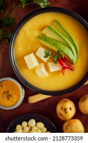 Ecuadorian locro de papa a traditional potato and cheese soup served with avocado and hominy. It’s on a wooden background - Shutterstock ID 2128773359