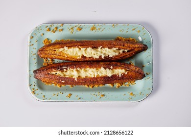 Ecuadorian maduro con queso consists of baked ripe plantains stuffed with cheese. It’s on a white background.  - Shutterstock ID 2128656122