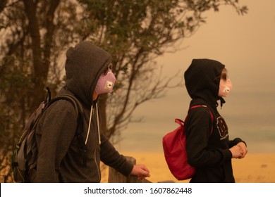 Eden, Australia - December 31, 2019: Tourists, A Father And Daughter At The Beach In Eden By The Evacuation Center, Wearing Particulate Masks And Sun Glasses To Avoid The Dense Orange Bushfire Haze.