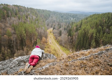 At the edge of a breathtaking valley, a solitary person gazes over the vast greenery below, embodying the spirit of adventure and exploration of natures wonders - Powered by Shutterstock