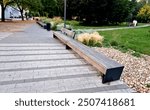 edge of the elevated terrace overlooking the park is a concrete long flowerpot with wood paneling and a rectangular bench. is part of the city promenade on the street and square