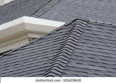 edge of Roof shingles on top of the house, dark asphalt tiles on the roof background. - Shutterstock ID 1056238658