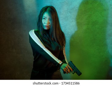 Edgy Cinematic Portrait Of Young Attractive And Dangerous Special Agent Woman Or Asian Mobster Girl Holding Handgun Pointing The Gun Fierce In Hollywood Movie Style