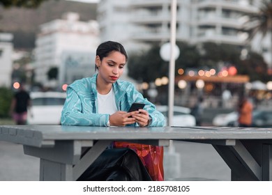 Edgy, Sad And Lonely Woman Texting On Social Media Dating App On A Phone And Looking Serious, Depressed Or Bored Outside In An Urban City. A Single Girl Posting About Her Bad Emotional Breakup