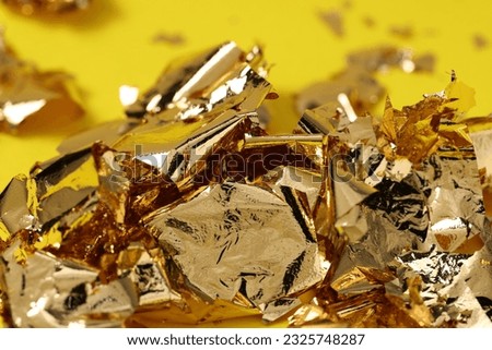 Edible gold leaf on yellow background, closeup