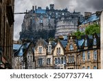 Edinburgh Castle with a moody and dark sky in the background and typical architecture in the foreground.