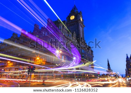 Edinburgh at night scene with Lights streak from high-sided vehicles on Princess street and Balmoral hotel on background