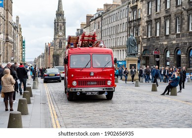 Edinburgh Scotland October 2019 Classic Old Red Silver Bedford Fire Engine Service With Wooden Extendable Ladder Driving On High Street Cobble Stones Shoppers Watching Church Sunny City Centre 