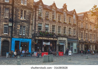 EDINBURGH, SCOTLAND - SEPTEMBER 16, 2014: Row Of Pubs At Grassmarket In An Old Town. Former Place Of Public Execution. People Sitting And Drinking Outside