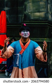 Edinburgh, United Kingdom, 3 Of August 2018 A Street Artist Standing Up Dressed Like An Asian Person And Wearing Makeup Rising His Hands While Doing A Show In The City Center