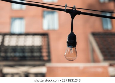 An Edison bulb on a string outside a brick building