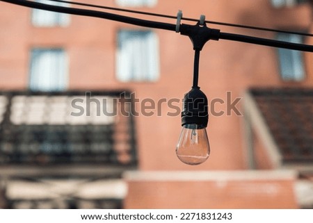 An Edison bulb on a string outside a brick building
